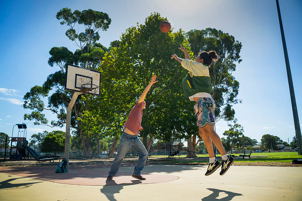 Two young people playing basketball on an outside basketball court