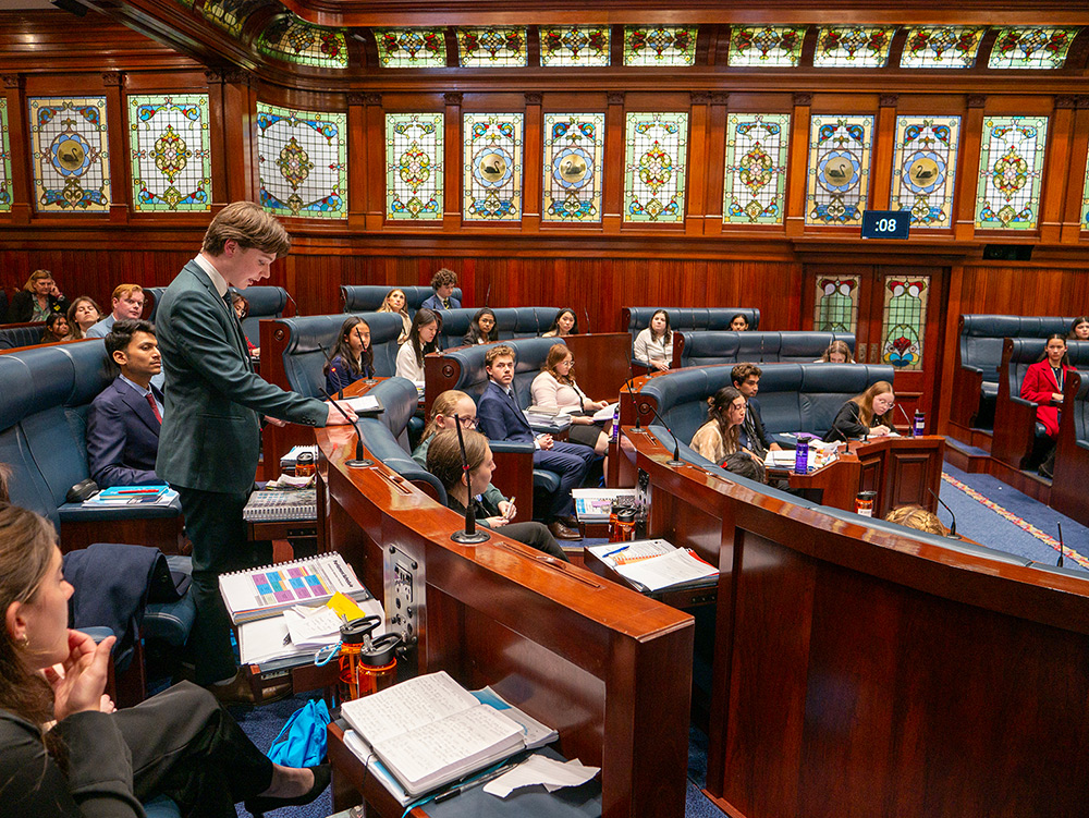 Young people watching their peer present a speech in the chambers of the Parliamen of Western Australia as part of the Youth Parliament Program