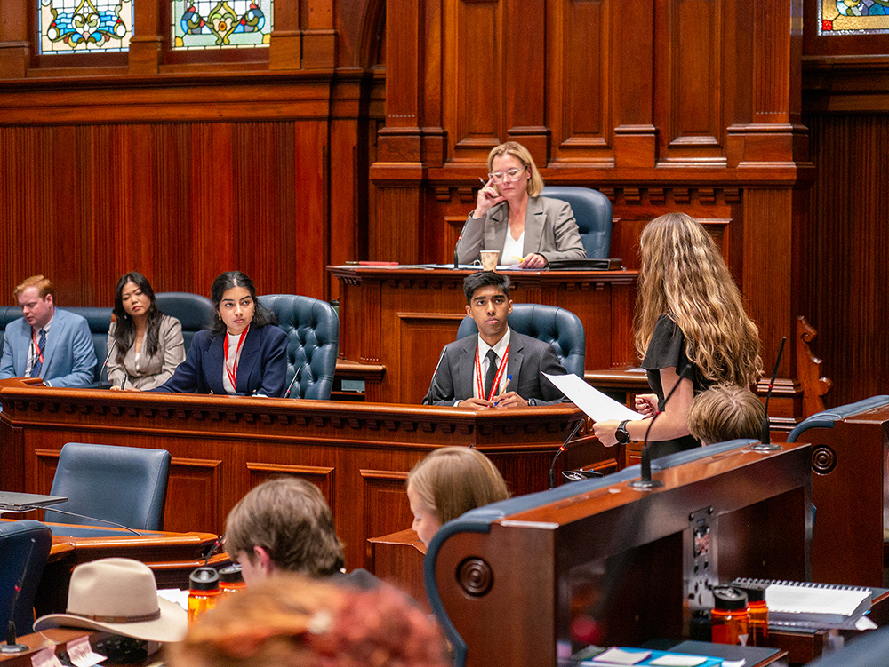 Group of young people and politician Hannah Beazley watching fellow young person give a speech in the chambers of the Parliament of Western Australia during the Youth Parliament program