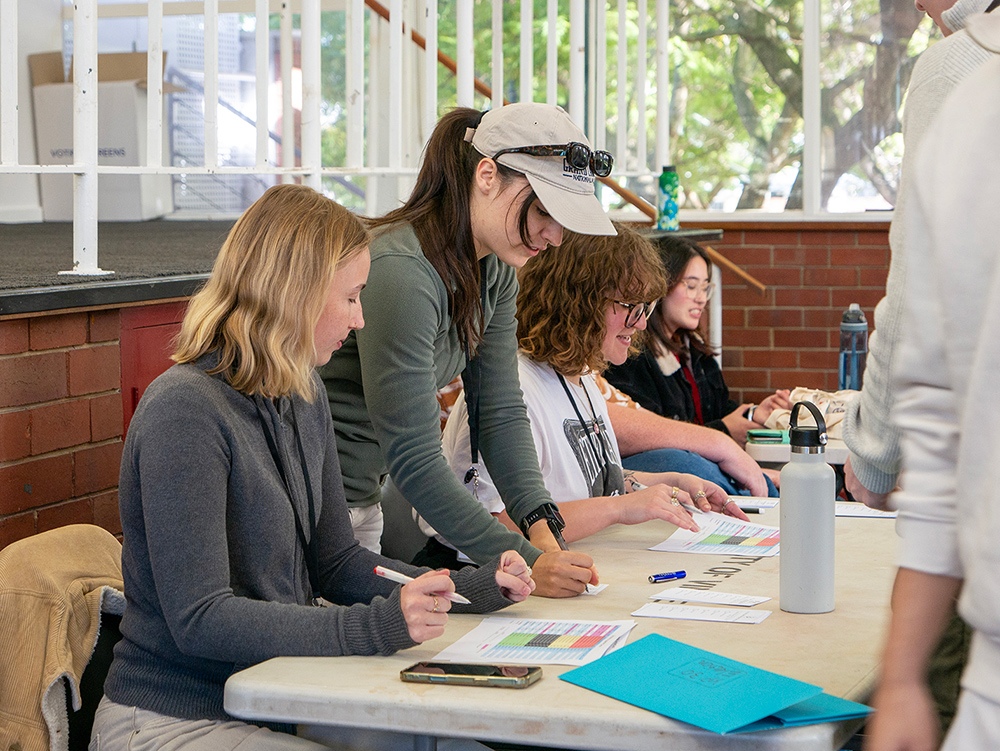 Young people collaborating around a table during a Y WA Youth Parliament training day, reviewing documents and worksheets together