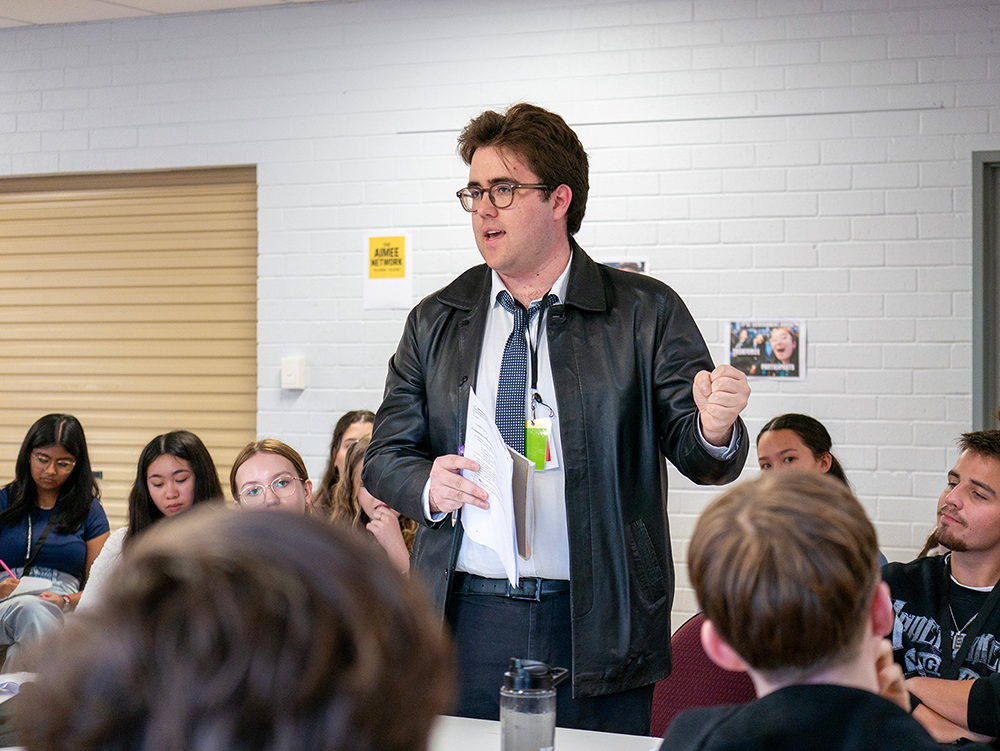 Young person standing up and giving instructions to group of other young people