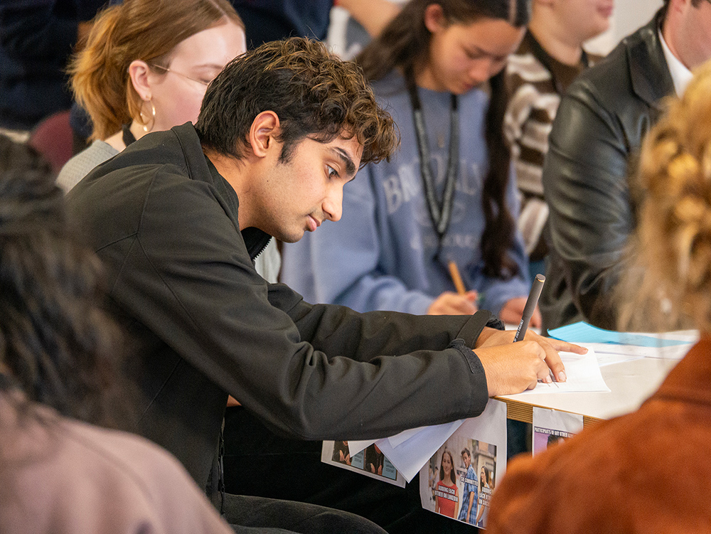 Diverse group of young people writing down important information during training day as part of the Youth Parliament program