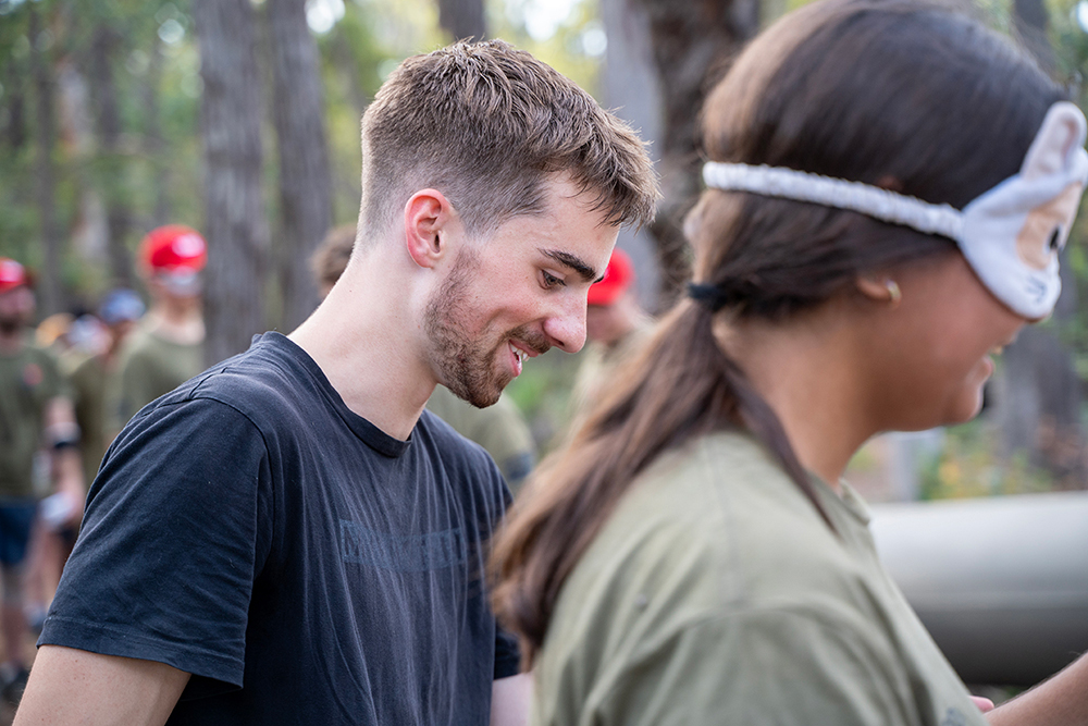 Young adult engaging in conversation with person wearing cap at outdoor community gathering