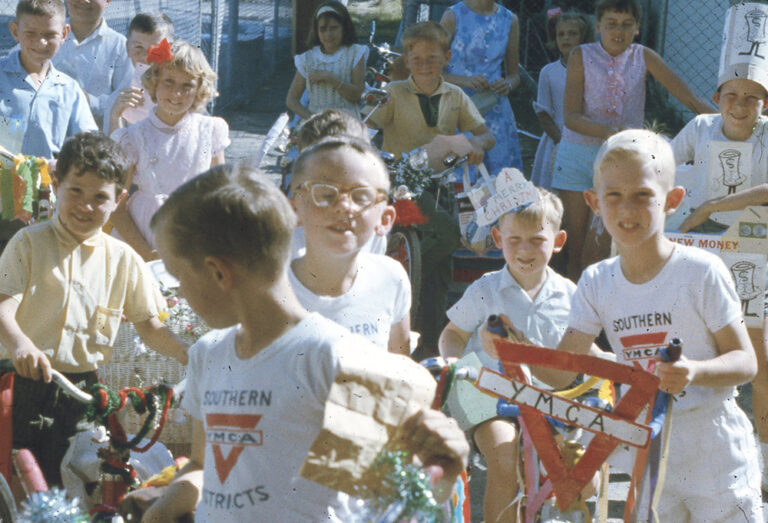 Vintage 1950s photo of children in Southern YMCA shirts at a decorated bike parade event.