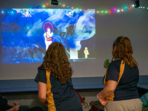Two young people playing just dance in a room at youth centre