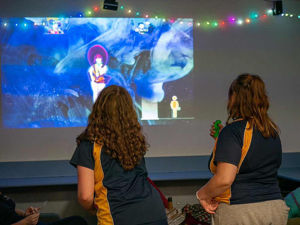 Two young people playing just dance in a room at youth centre