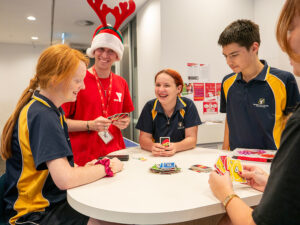 Group of young people and case worker playing uno together at a table