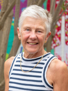 Smiling Y WA Board member Kendal in a navy striped top, photographed outdoors against a colourful mural backdrop.