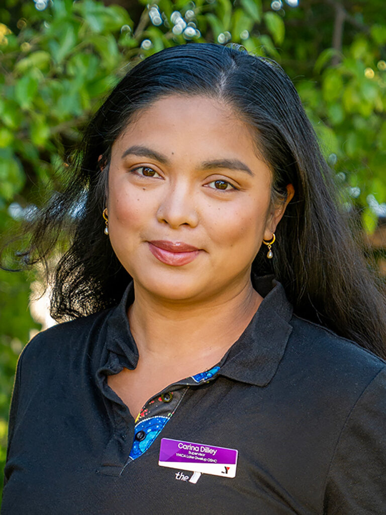 Professional headshot of smiling OSHC supervisor in Y WA uniform with name badge outdoors