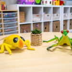 Toy frog and chameleon figures with small plant on table in organised early learning space