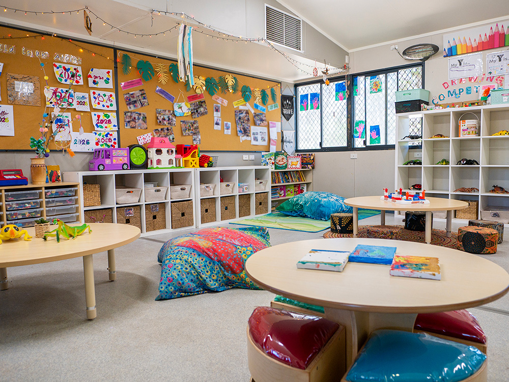 Organised early learning room with play areas, storage systems, floor cushions and educational displays