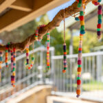 Colorful beaded craft hanging from tree branch at OSHC outdoor play area