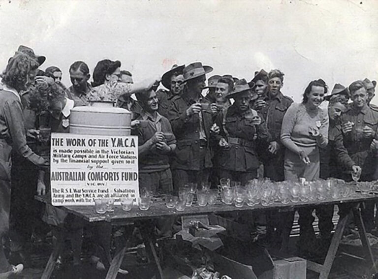Vintage black and white photo of YMCA volunteers serving drinks to Australian soldiers, supported by the Australian Comforts Fund.