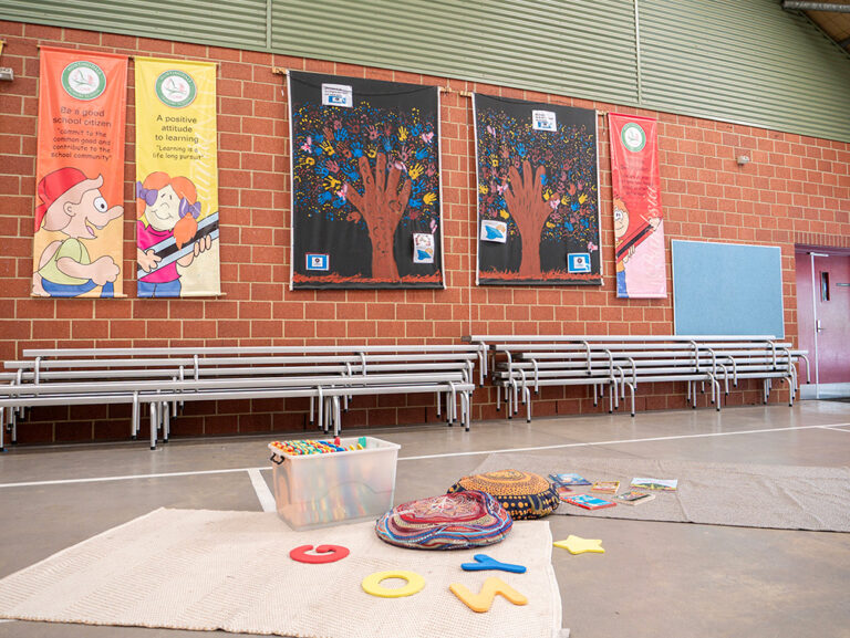 OSHC activity setup with educational posters, handprint art, benches and floor games ready