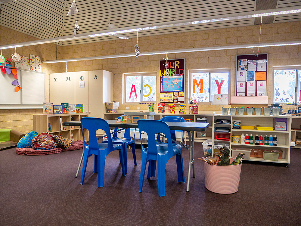 OSHC activity room with blue plastic chairs, craft storage, colorful letter displays and floor cushions