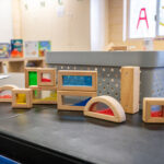 Wooden sensory blocks with colored panels arranged on table in OSHC learning space