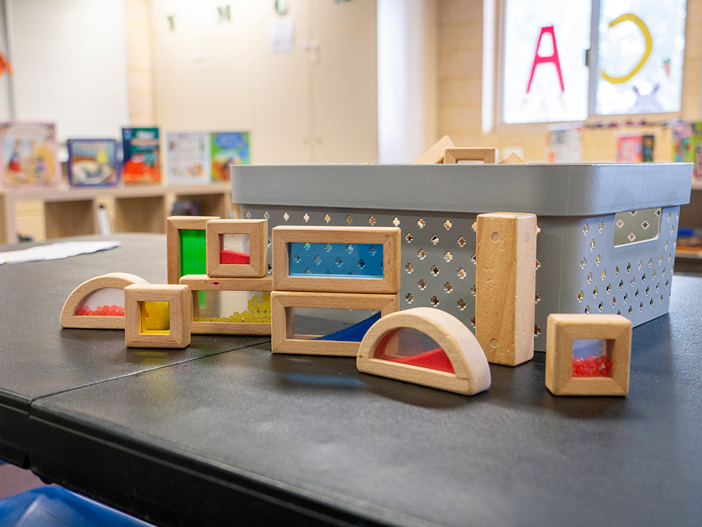 Wooden sensory blocks with colored panels arranged on table in OSHC learning space
