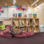 OSHC reading nook with floor cushions, book shelves, whiteboard and children's artwork displays