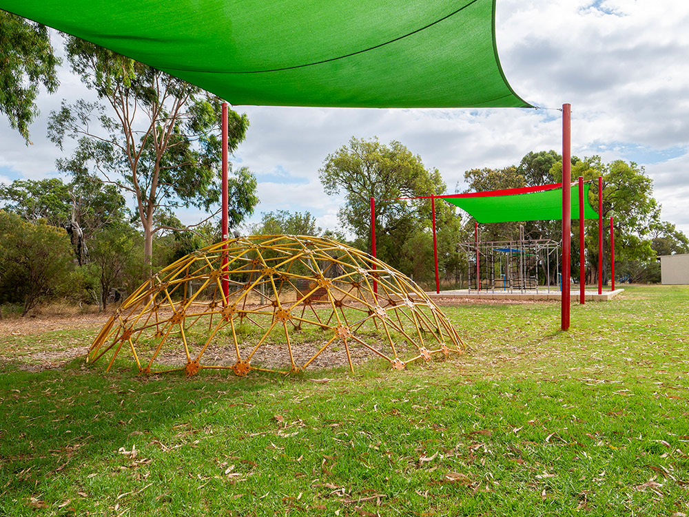 OSHC outdoor play space with climbing dome, shade sails and grassed area