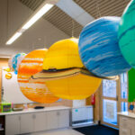 Colourful hanging solar system planet models suspended from OSHC classroom ceiling