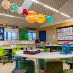 Bright OSHC classroom with solar system display hanging from ceiling and activity tables