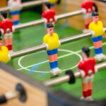 Close-up of foosball table player figures on green pitch at OSHC games areaY