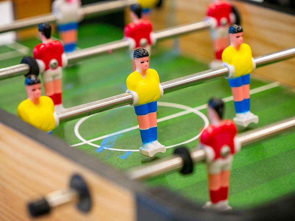 Close-up of foosball table player figures on green pitch at OSHC games areaY