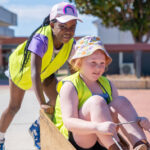 Colourful plastic dollhouse and treehouse play sets on rug in spacious OSHC hall
