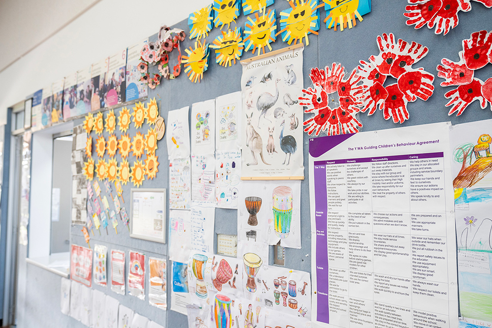OSHC display wall with children's handprint art, sun crafts and Y WA behaviour agreement