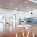 Spacious OSHC hall with polished timber floors, play mats and display boards