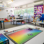 OSHC room with colourful board game on table, activity areas and multicultural flag displays