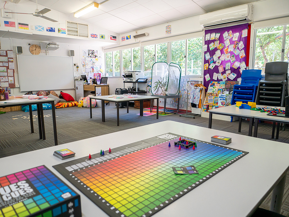 OSHC room with colourful board game on table, activity areas and multicultural flag displays
