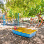 OSHC nature play area with boat sandpit, wooden climbing sculpture and colourful equipment
