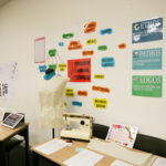 Student artwork and posters displayed on wall above desk at the Y School