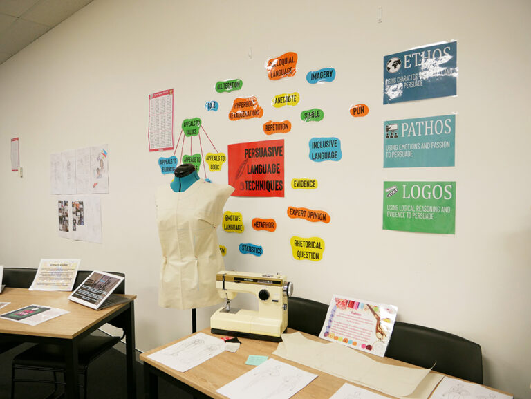Student artwork and posters displayed on wall above desk at the Y School