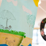 Children's paper craft showing outdoor play scenes and stained glass ornament at OSHC