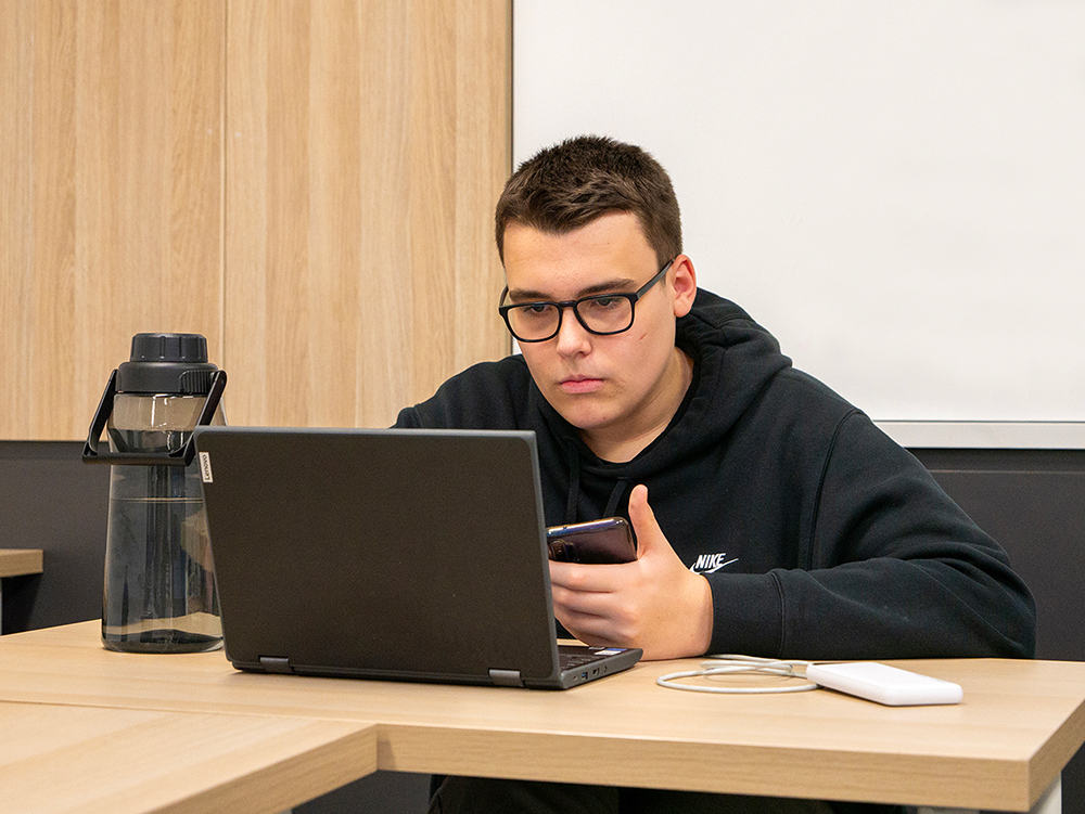 Y School student wearing glasses while working on his laptop at desk