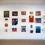 A variety of brightly coloured student artwork displayed on the wall and shelving units