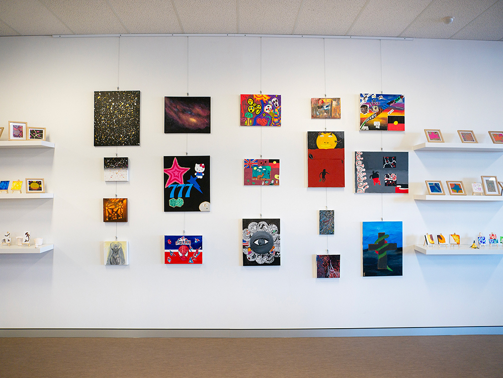 A variety of brightly coloured student artwork displayed on the wall and shelving units