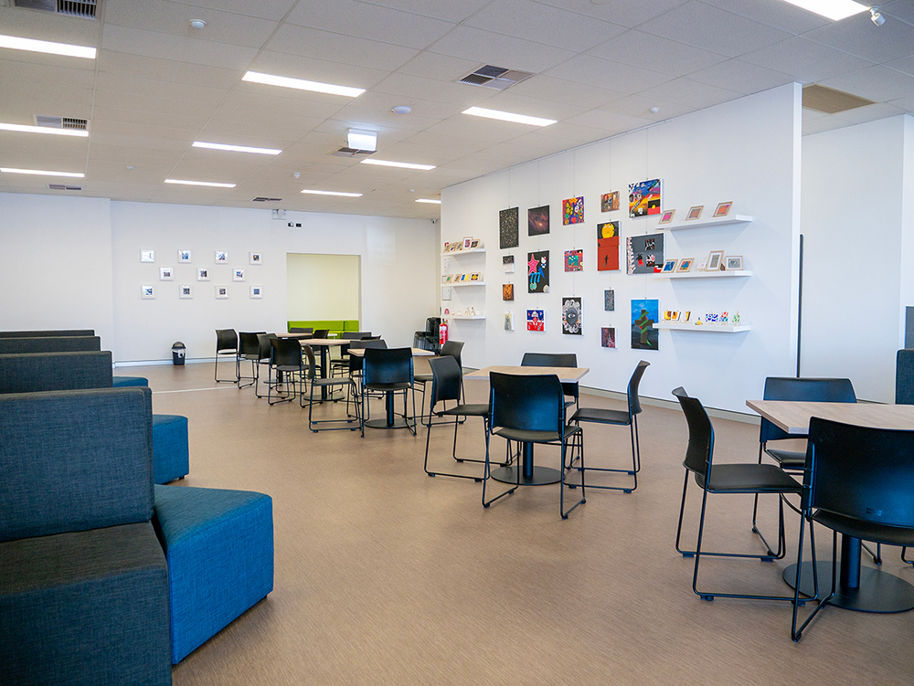 Classroom at Y school with tables, chairs, couches and student artwork displayed on the walls