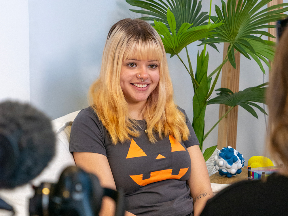 Y School student smiling while sitting on couch in a room at the Y School