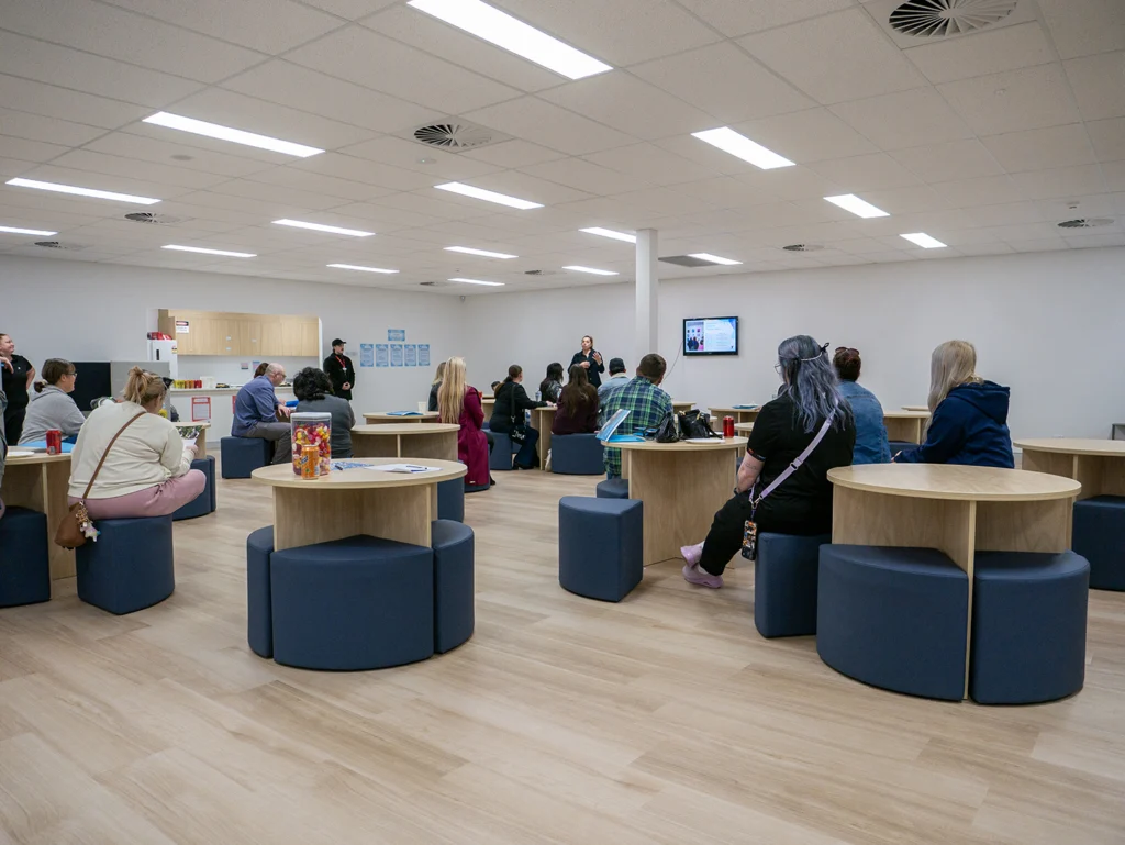 A large room at the Y School Mirrabooka Junior Campus filled with parents and teachers. There is a teacher at the front of the room presenting.