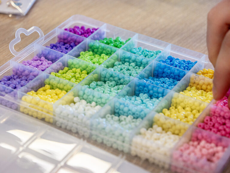 Close up of various rainbow coloured beads for bracelet making on a table at the Y School