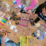 Overhead shot of young Y School students engaging in bead making activity at a table