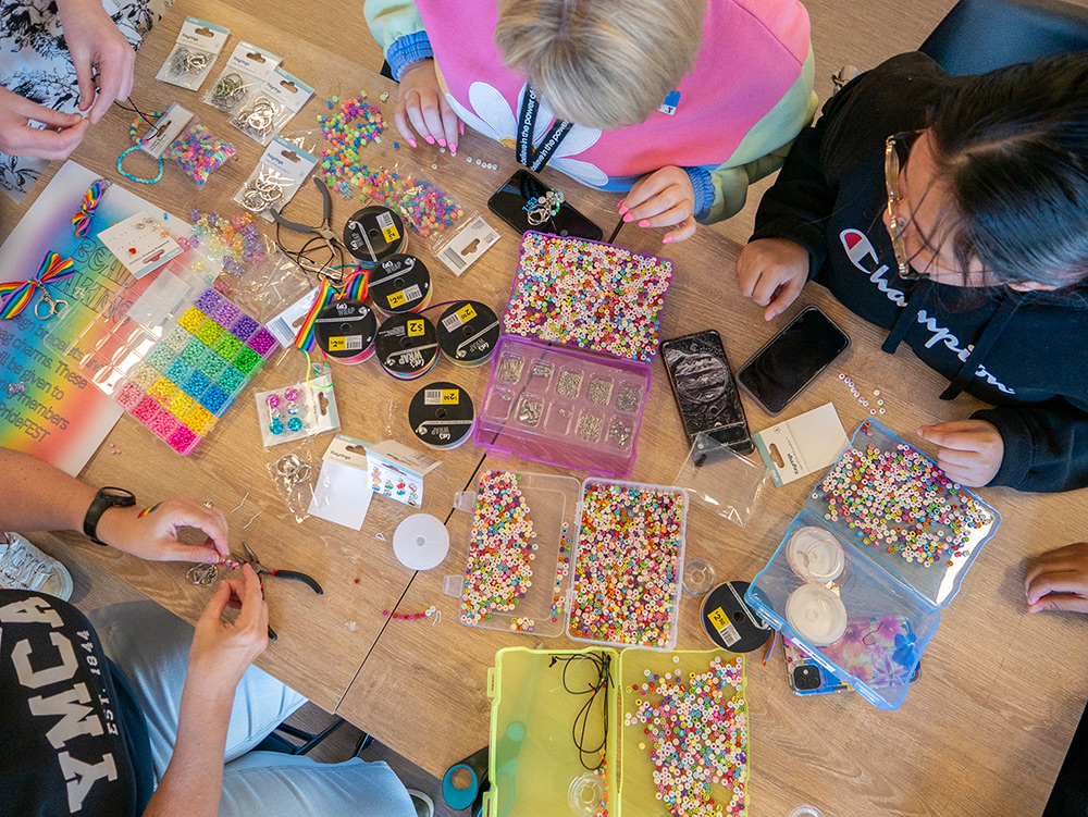 Overhead shot of young Y School students engaging in bead making activity at a table