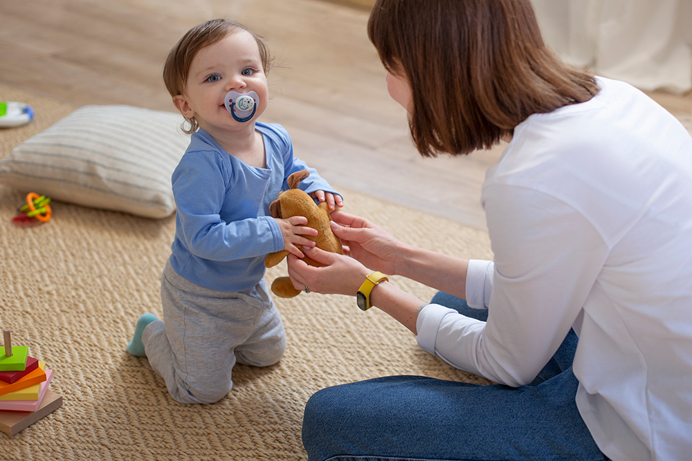 Mother and child playing with age appropriate toy on carpet
