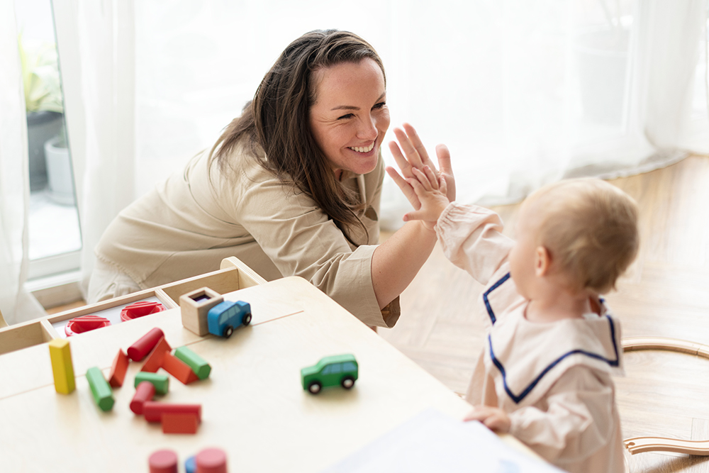 Mother hi fiving her child while sitting at a play table