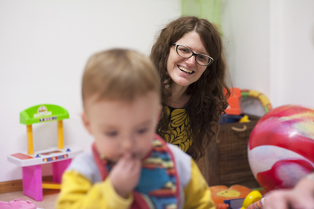 Mother smiling at her child as he plays