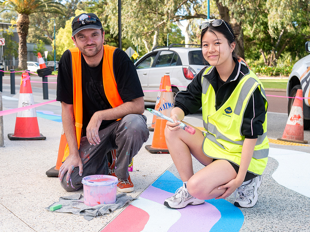 An artist and young person painting a street art mural together
