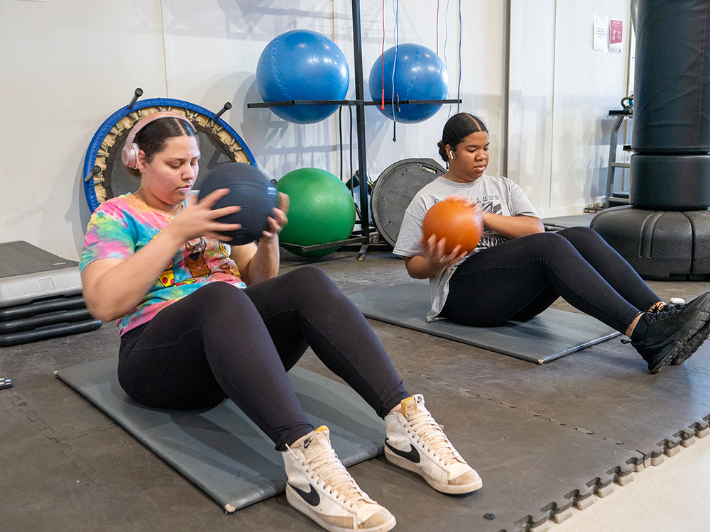 Two young people exercising with weighted balls in the gym